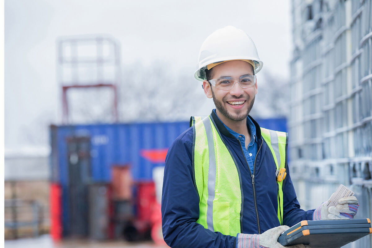 A remote employee at a construction site smiling while completing his engagement survey using Teamgage.